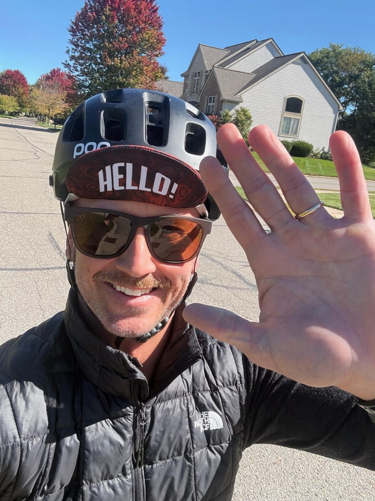 Kristian waving from his bike on a neighborhood street